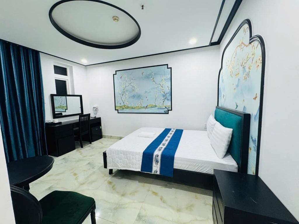 Ein Hotelzimmer mit Bett, Schreibtisch, Stuhl und einem großen Gemälde an der Wand.