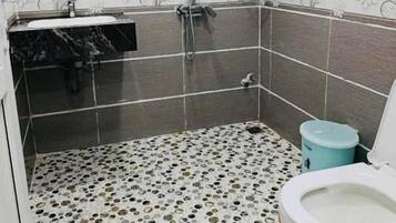 Een badkamer met een douche, wastafel en toilet.