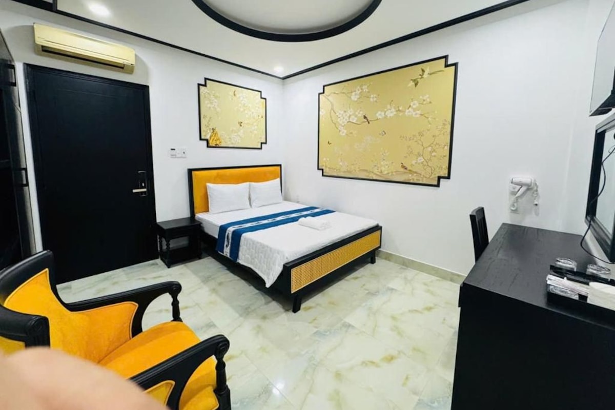 A hotel room with a bed, a desk, a chair, and artwork on the walls.