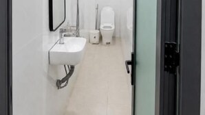 A modern bathroom with a glass shower enclosure, a sink, and a toilet. - Gia Bao Hotel Near Tan Son Nhat Airport (Tân Bình)