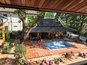 Ein überdachter Außenbereich mit Pool, umgeben von Kübelpflanzen und einer Pflasterterrasse.