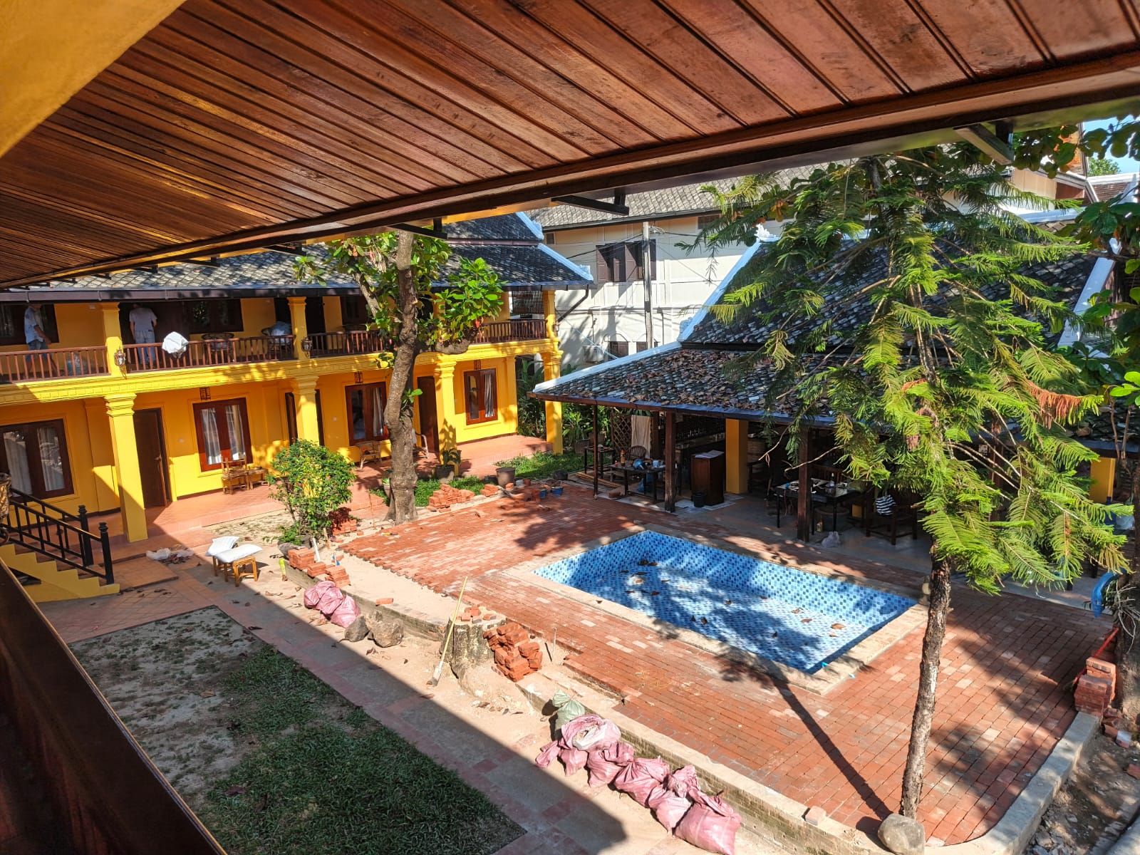 Une cour avec une piscine, un espace salon abrité et un bâtiment jaune doté de nombreux balcons.