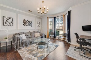 A living room with a sofa, coffee table, and chairs, a dining area with a table and chairs, and artwork on the walls. - Perfect 5-bedroom house with AC in soothing Plano neighborhood (Plano)