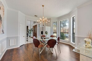 A dining area with a chandelier, wooden flooring, and large windows. - Perfect 5-bedroom house with AC in soothing Plano neighborhood (Plano)