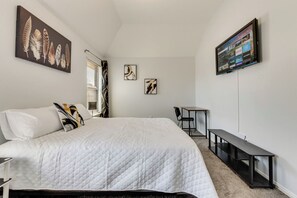 A bedroom with a bed, a desk, a chair, and a TV mounted on the wall. - Perfect 5-bedroom house with AC in soothing Plano neighborhood (Plano)