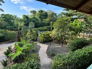 A garden with a gravel path, various plants, and a small structure in the background. - Tropical Lodge 
Hidden Hideaway-House (Playa Grande)