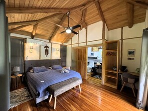 A bedroom with a bed, bedside tables, a ceiling fan, and a wooden floor. - Tropical Lodge The Hidden Hideaway (Playa Grande)