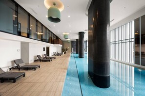 A modern indoor swimming pool with lounge chairs and large pillars. - Free Parking. Walk to Marvel Stadium & CBD (West Melbourne)