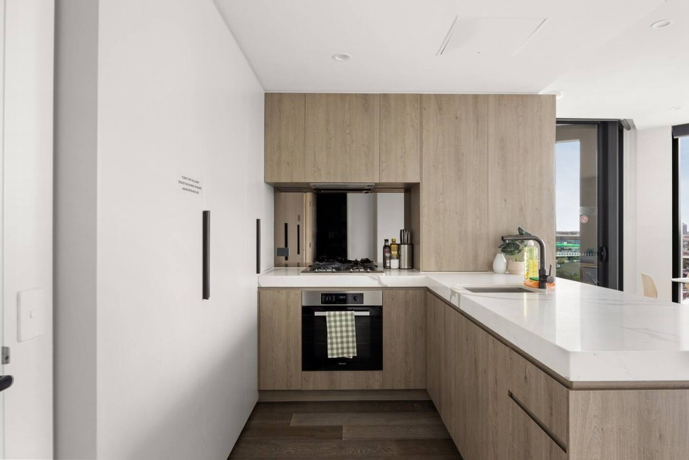 Een moderne keuken met een inbouwvaatwasser, een kookplaat en een groot raam met uitzicht op de stad.