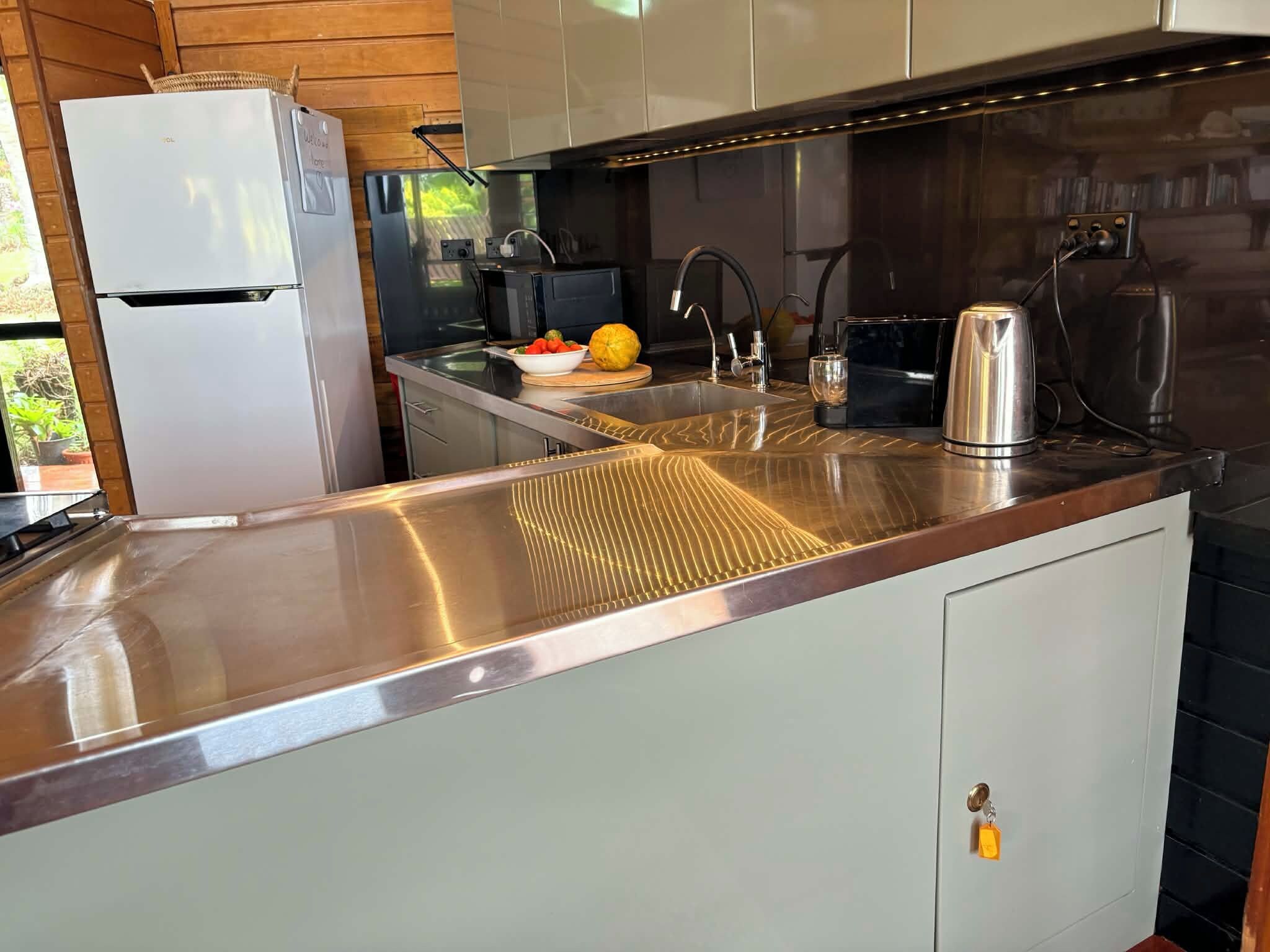 Une cuisine moderne dotée d’appareils électroménagers en acier inoxydable, d’un évier encastré et d’un plafond en bois.