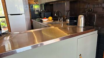 Une cuisine moderne dotée d’appareils électroménagers en acier inoxydable, d’un évier encastré et d’un plafond en bois.