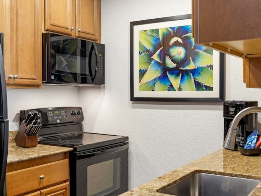 A kitchen with wooden cabinets, a microwave, a stove, and a sink.