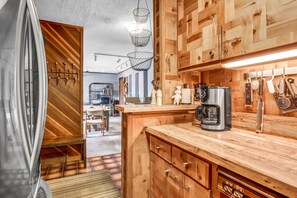 Eine moderne Küche mit Holzschränken, einer Kaffeemaschine und diversen Küchengeräten.