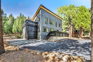Ein zweigeschossiges Gebäude mit Garage, umgeben von Bäumen und einem Kiesweg.