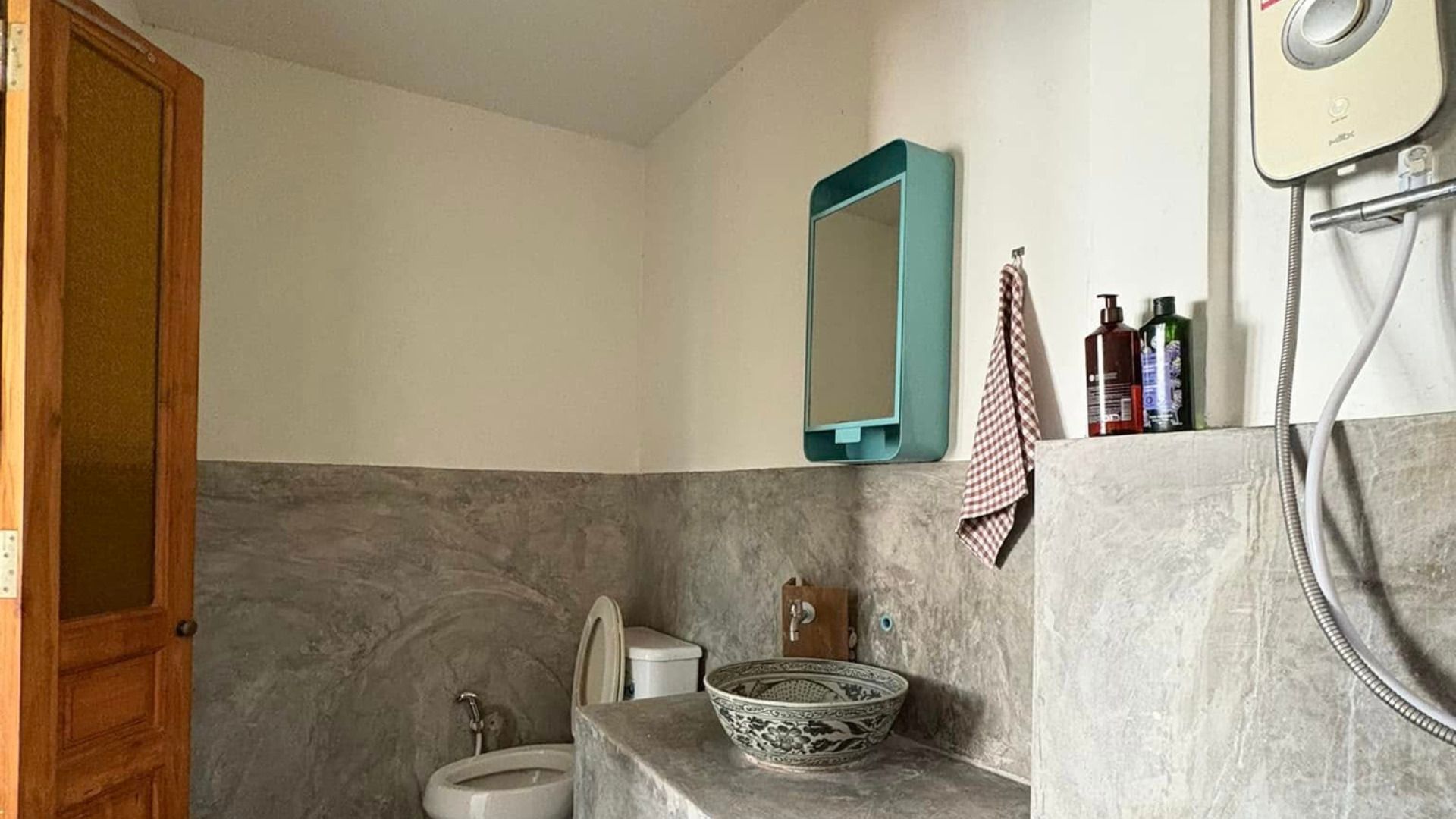 Een badkamer met toilet, bidet en een wastafel met decoratieve kom.