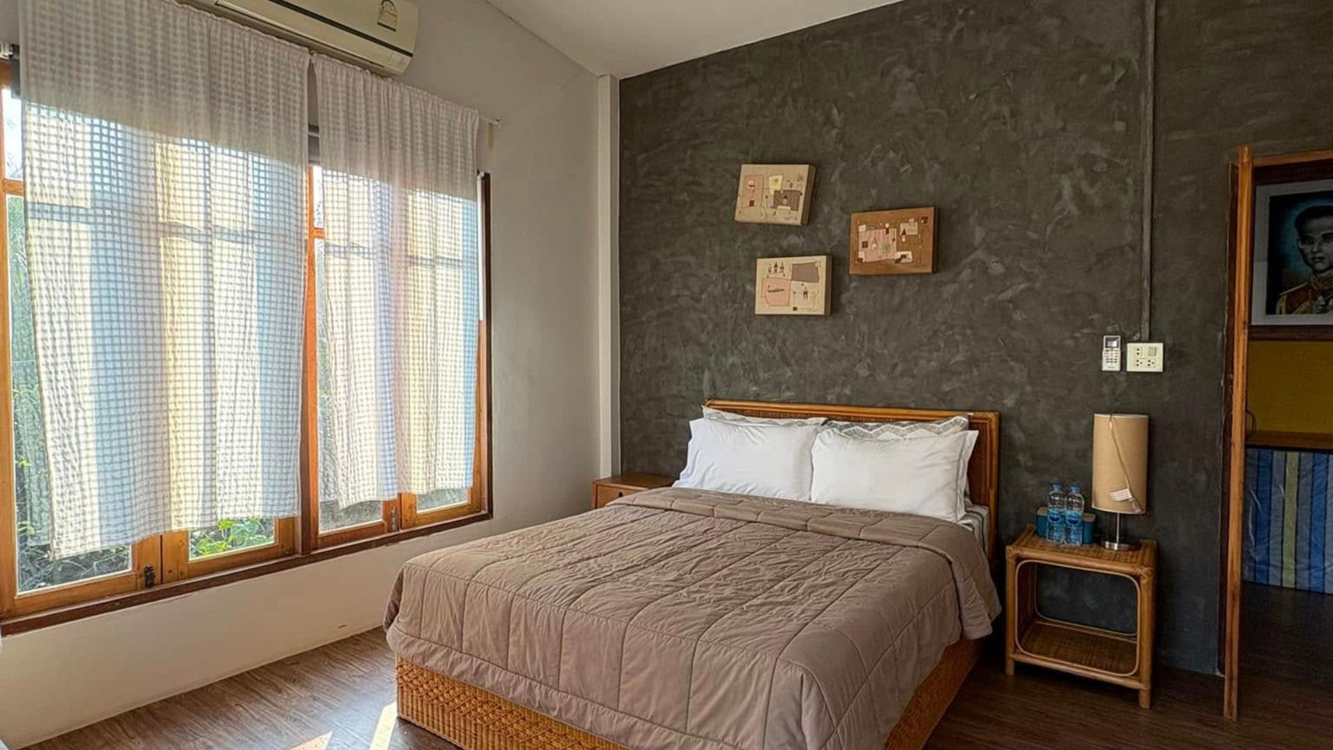 Un dormitorio con cama, mesita de noche, lámpara y una pared decorada con marcos.