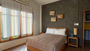 Un dormitorio con cama, mesita de noche, lámpara y una pared decorada con marcos.