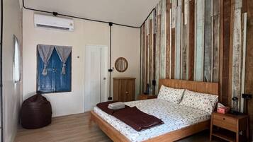 A bedroom with a wooden bed, a bedside table, a wardrobe, and a wall-mounted air conditioner.