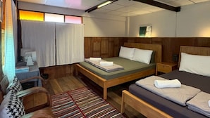 A room with a bed, a bench, a desk, a chair, and a window with curtains. - Amphawa Hideaway (Amphawa)