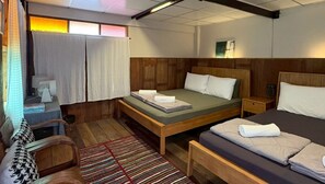 Una habitación con cama, un banco, un escritorio, una silla y una ventana con cortinas.