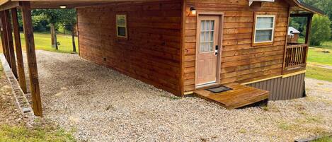 A wooden cabin with a covered porch, a door, and a window.