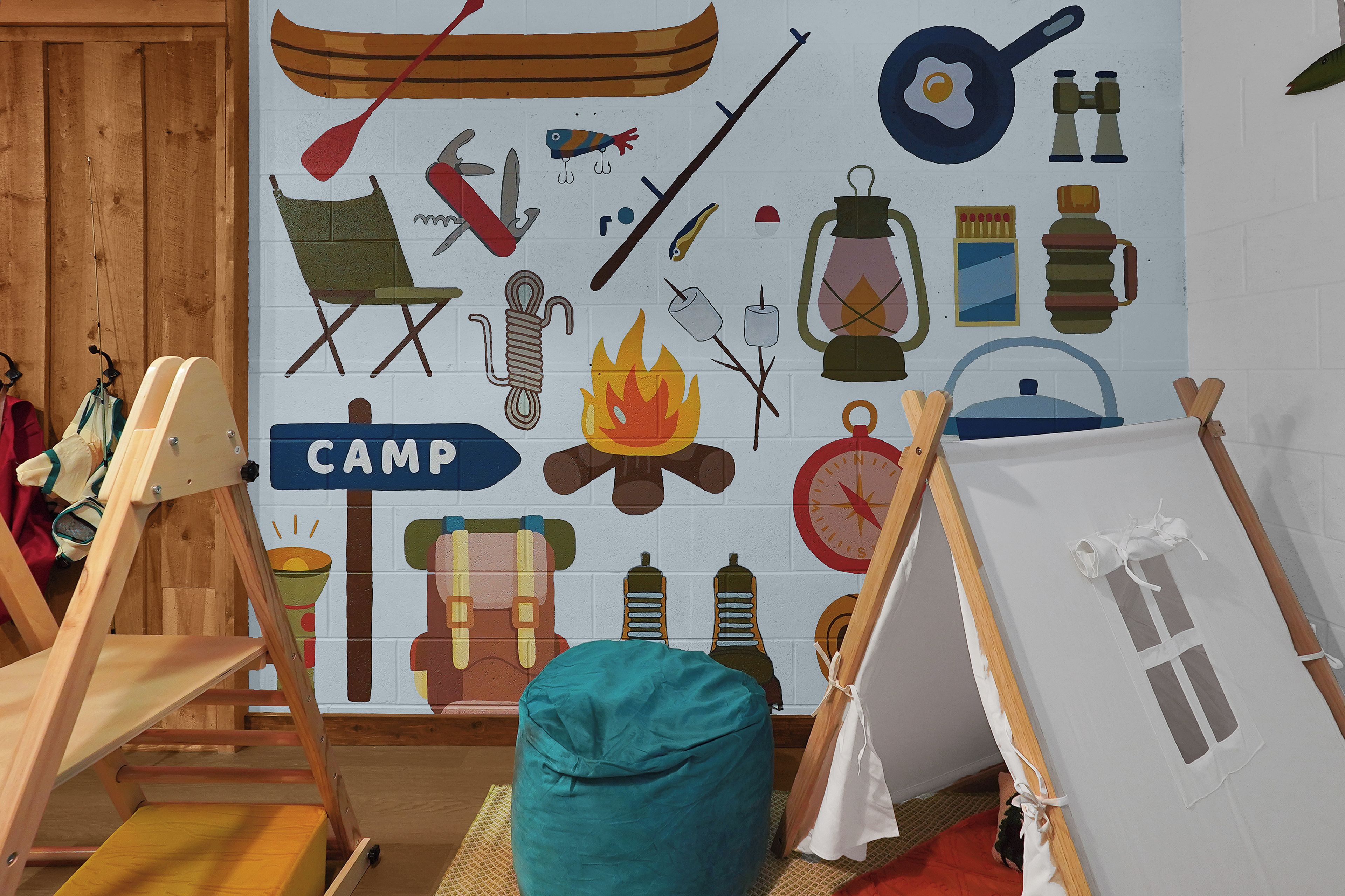 A room with a wall mural depicting camping gear and a tent labeled 'CAMP'.