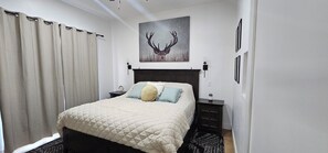 Una camera da letto con un letto, un comodino, una lampada a parete e un quadro raffigurante un cervo.