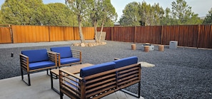 An outdoor seating area with wooden furniture and a gravel ground.