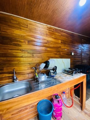 Una cocina con paneles de madera, un lavamanos, una tetera y una mesa con una tetera y un radio.