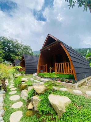A wooden cabin with a sloped roof, a porch, and a stone pathway leading to it.