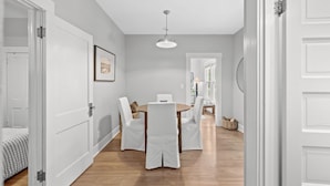A dining area with a round table and chairs, a ceiling light, and a door leading to another room. - StayHaus - The Meridian Flat (St. Petersburg)