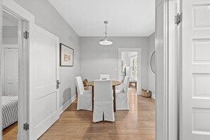 A dining area with a round table and chairs, a ceiling light, and a door leading to another room. - StayHaus - The Meridian Flat (St. Petersburg)