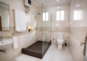 Une salle de bain moderne avec une douche à parois de verre, un lavabo blanc et des toilettes.