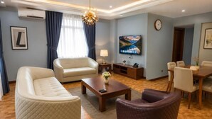 Uma sala de estar moderna com sofá, poltrona, mesa de centro e TV de tela plana na parede.