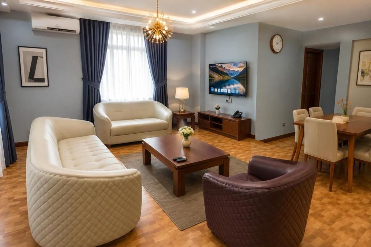 Un salon moderne comprenant un canapé, un fauteuil, une table basse et un téléviseur fixé au mur.