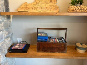 A wooden shelf with a map, a basket of DVDs, and a Sony Blu-ray player. - Mountain Glory - New Modern Cabin with Hot Tub and Mountain Views (Rileyville)