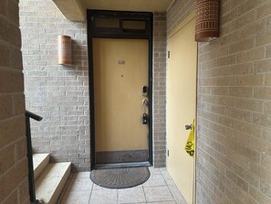 A hotel entrance with a yellow door, a keypad lock, and a doormat. - Apartment on South Padre Island (South Padre Island)