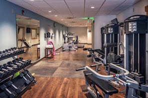 Une salle de sport équipée de matériel d’exercice, d’un miroir et d’un tapis de course.