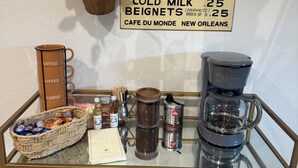 A coffee station with a sign indicating prices for coffee, cold milk, and beignets. - Fabulous 3-bedroom house with AC in vibrant Houston suburban neighborhood. (Houston)