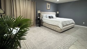 A bedroom with a bed, a ceiling fan, a nightstand, a lamp, a potted plant, and a patterned rug. - Fabulous 3-bedroom house with AC in vibrant Houston suburban neighborhood. (Houston)