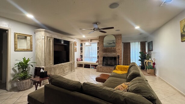 A living room with a fireplace, a television, and a ceiling fan. - Fabulous 3-bedroom house with AC in vibrant Houston suburban neighborhood. (Houston)