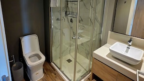 A modern bathroom with a glass-enclosed shower, a white toilet, and a vanity with a sink. - Modern Maho Studio Near Mullet Bay & Maho Beach (Maho)