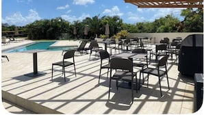 An outdoor patio with tables and chairs, a pool, and a pergola structure. - Modern Maho Studio Near Mullet Bay & Maho Beach (Maho)