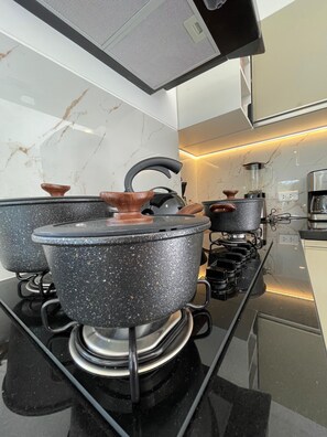 A kitchen with a gas stove, pots, and a coffee maker.