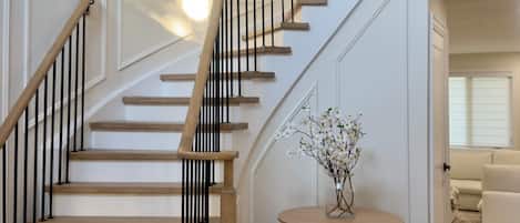 Un escalier avec des marches en bois et des rampes noires, menant à l’étage supérieur.
