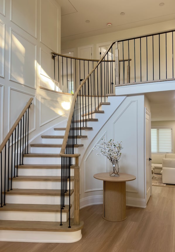 A staircase with a wooden finish and black railings, leading to an upper floor.