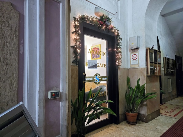 L’entrée d’un hôtel, avec un comptoir d’accueil, une enseigne indiquant « AKIN GATE » et une autre avec l’inscription « BIENVENUE ».
