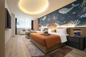 Una habitación de hotel con una cama grande, una mesita de noche, un mural en la pared y un televisor de pantalla plana.