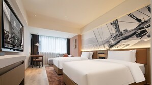 Una habitación de hotel con dos camas, un escritorio y un ventanal grande.