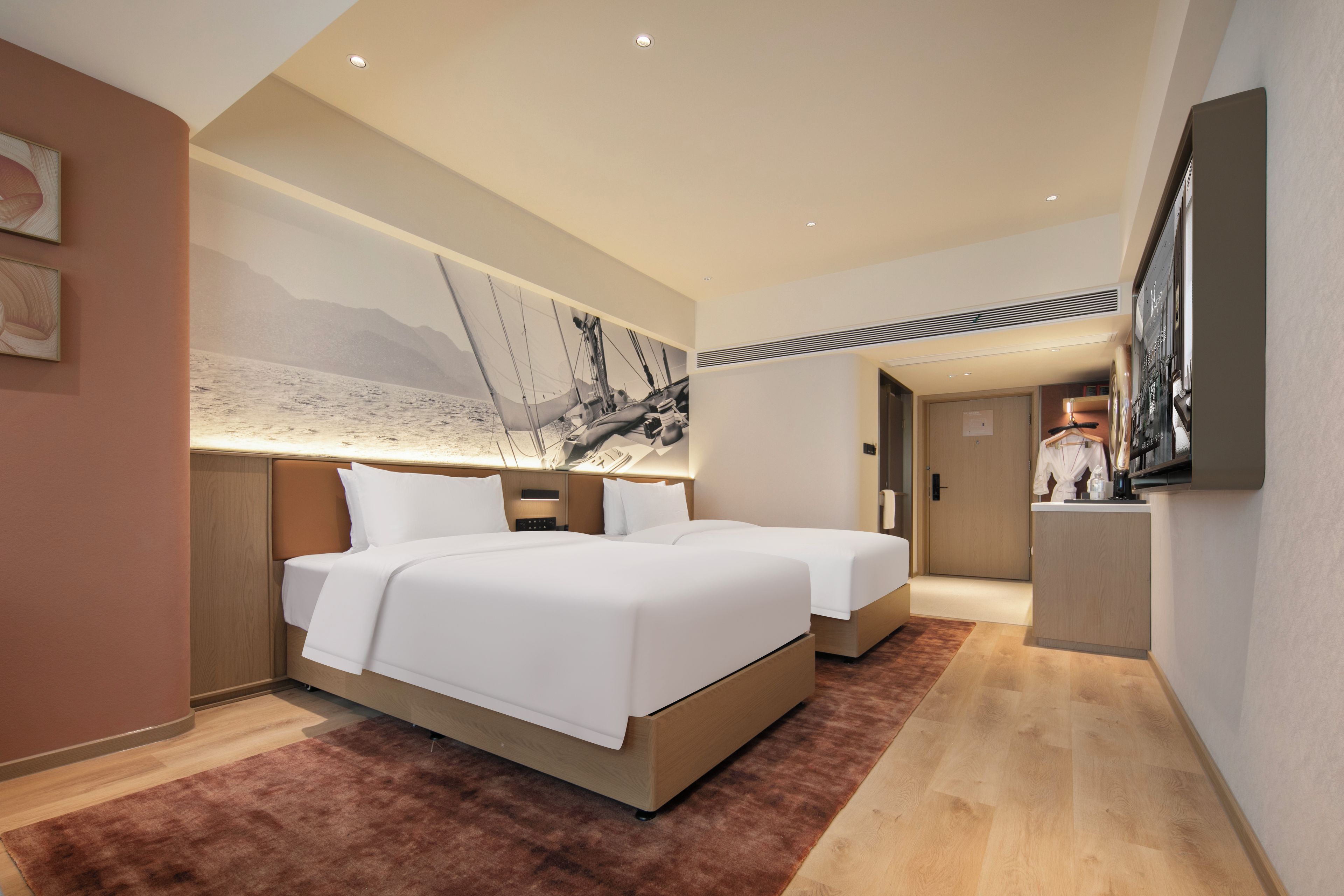 Quarto de hotel moderno com uma cama grande, uma escrivaninha e uma pintura de veleiros.